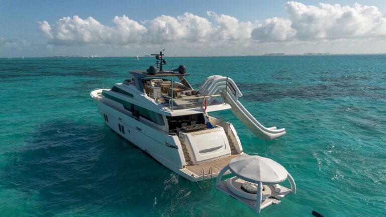 105 ft San Lorenzo luxury yacht charter at anchor in turquoise Caribbean near Cancun with inflatable water slide and floating island platform deployed