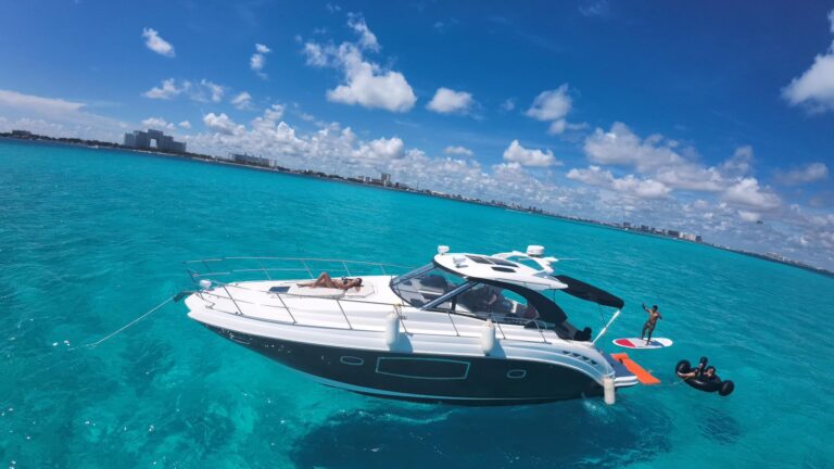 42 ft Premier yacht Itzae cruising past a pirate ship attraction in Cancun's lagoon with guests standing on the bow enjoying the ride, black and white hull gleaming