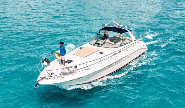 Crew member on bow of 42 ft Sea Ray Manatee luxury yacht charter cruising vivid turquoise Caribbean water, Cancun rental