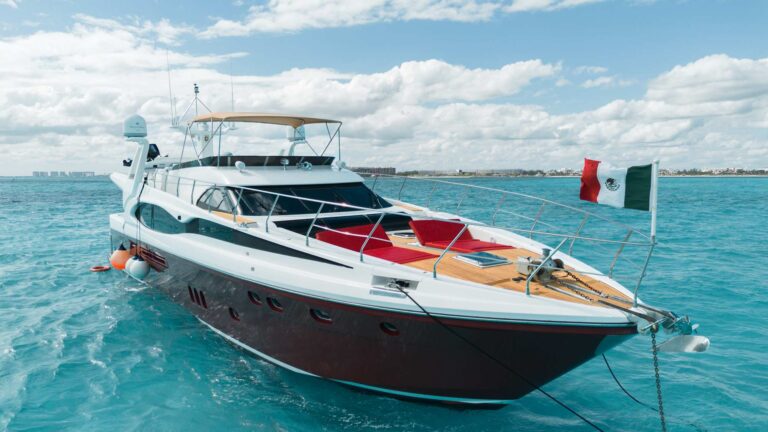 Bow-quarter aerial view of 80 ft Dyna Vive luxury yacht charter anchored in turquoise Caribbean sea under dramatic storm clouds
