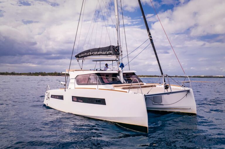 Front bow view of 34 ft Bali Davinci catamaran rental in crystal-clear turquoise water near a tropical sandy island, stunning catamaran charter at Riviera Maya Tulum