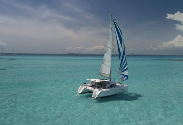 Lagoon 421 catamaran under full blue and white striped sail cruising in turquoise Caribbean water during a VIP all-inclusive charter from Cancun to Isla Mujeres