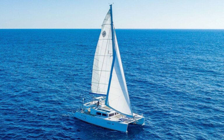 Aerial view of 48 ft Lagoon catamaran Chapter Two sailing under full white mainsail on deep blue Caribbean sea en route from Puerto Aventuras to Cozumel