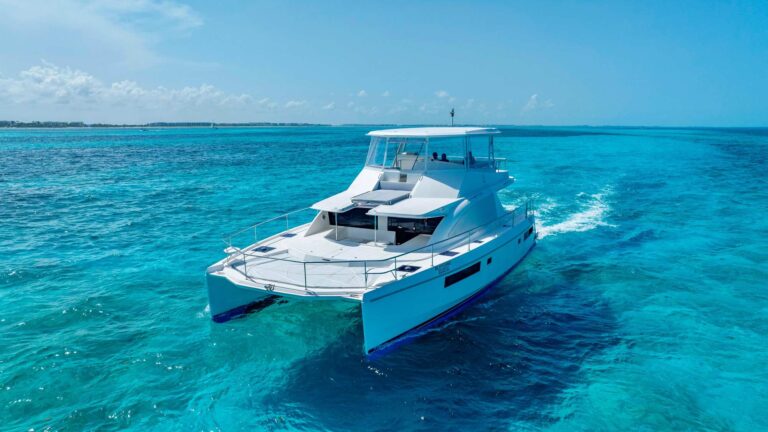 Side angle of 51 ft Leopard Blondie power catamaran on turquoise Caribbean reef water near Isla Mujeres, ready for luxury Cancun yacht charter rental.