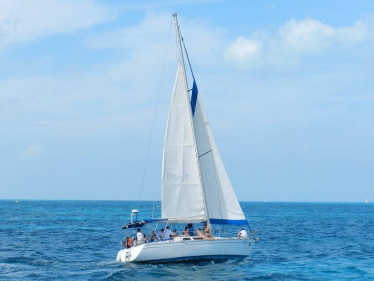 40 ft sailboat Xanadu charter under full mainsail and jib with group of guests on deck sailing the blue Caribbean sea near Cancun.